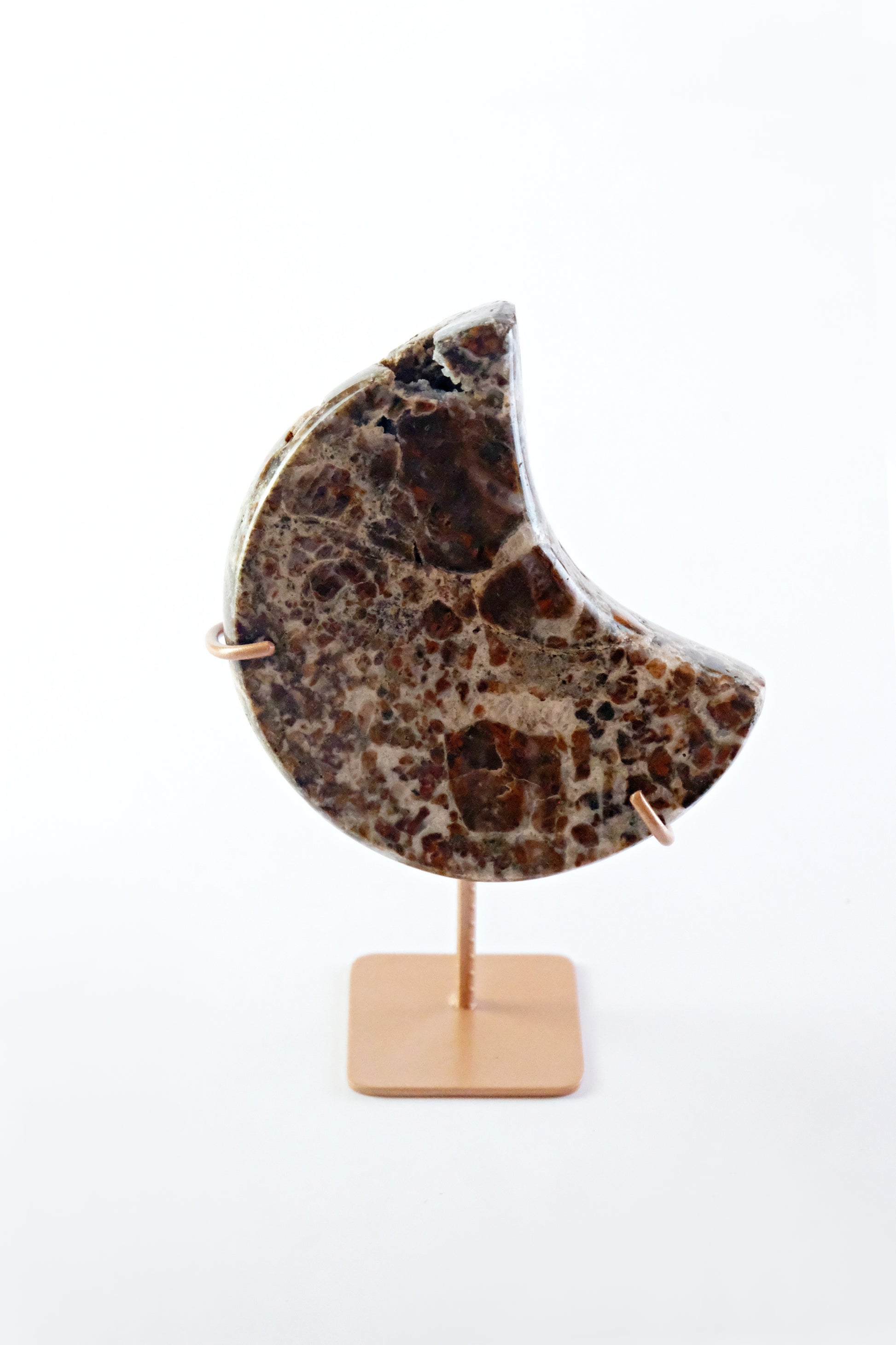 Decorative moon-shaped stone on a stand with a white background