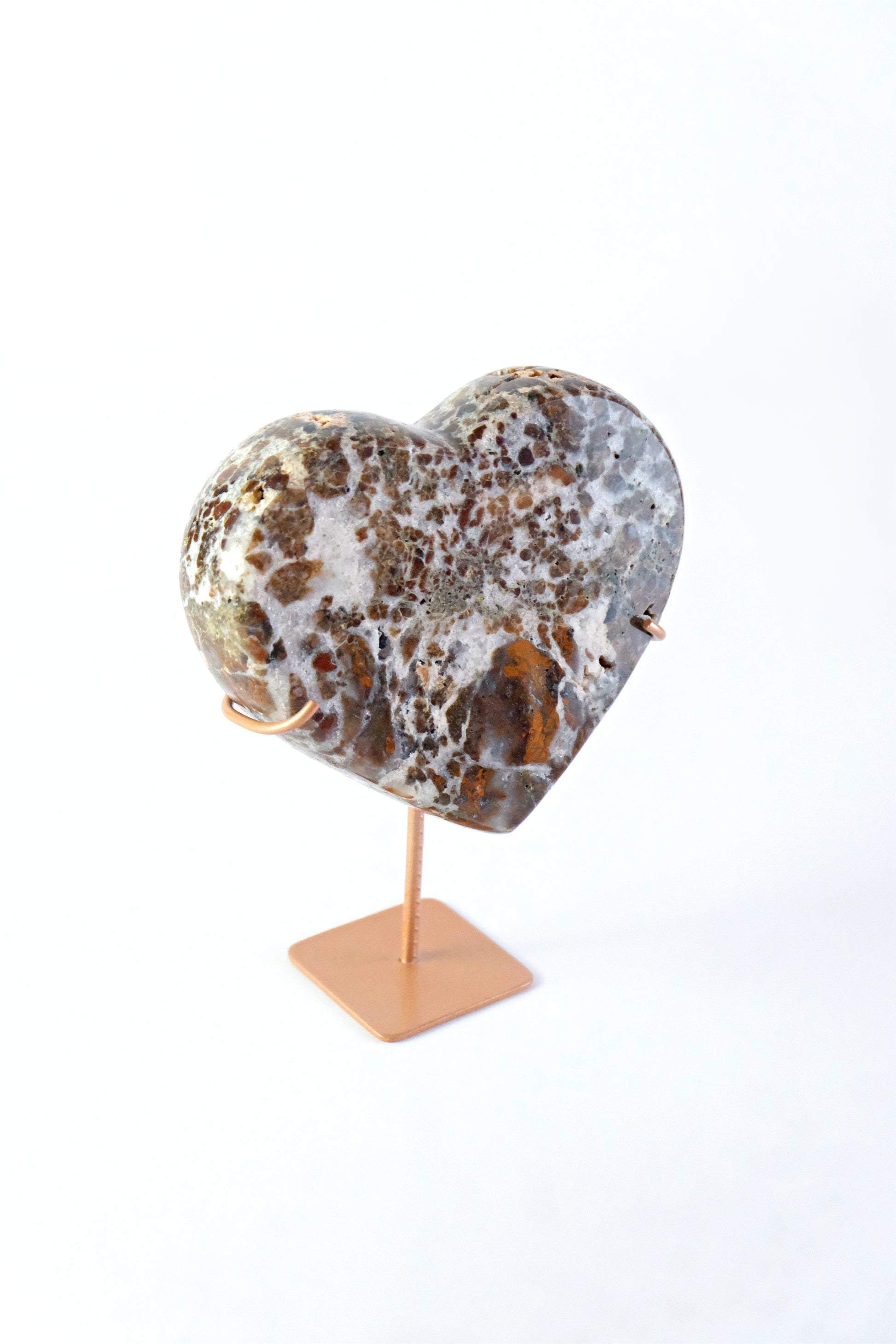 Marble-patterned heart-shaped object on a stand against a white background