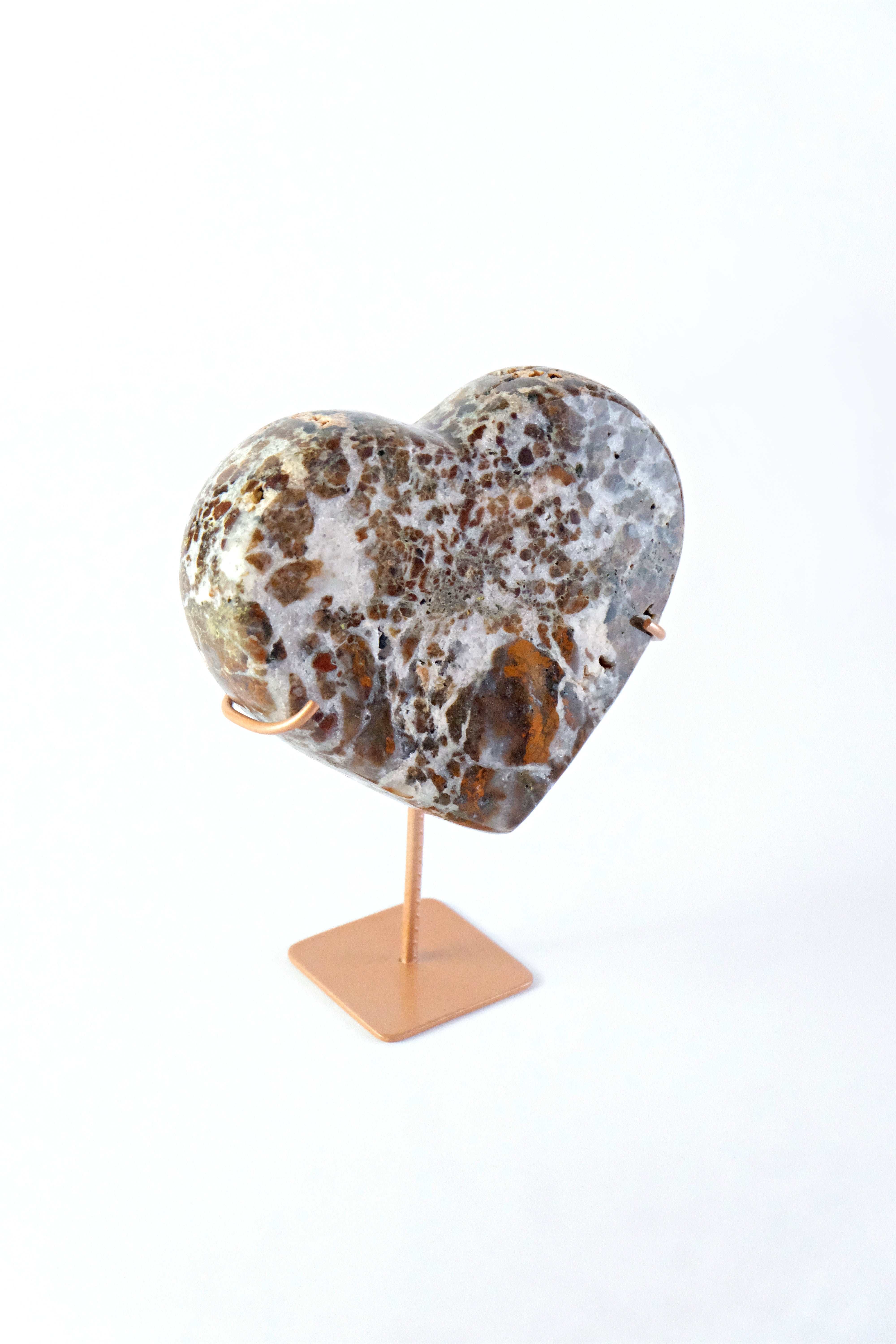 Marble-patterned heart-shaped object on a stand against a white background